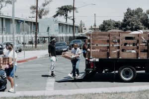 disaster relief man in black jacket and blue denim jeans standing beside brown wooden box trailer during daytime